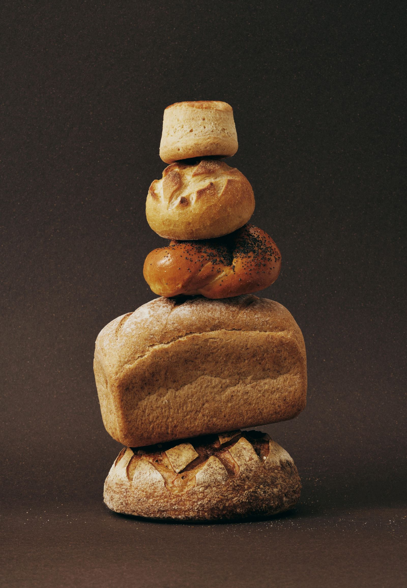 A stack of freshly baked breads resting on a warm brown background, perfect for showcasing the art of bread baking.