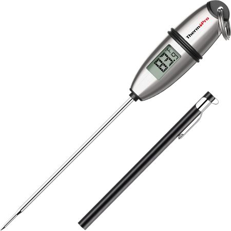 A digital thermometer alongside a pen and a traditional thermometer on a clean surface, showcasing temperature measurement tools.