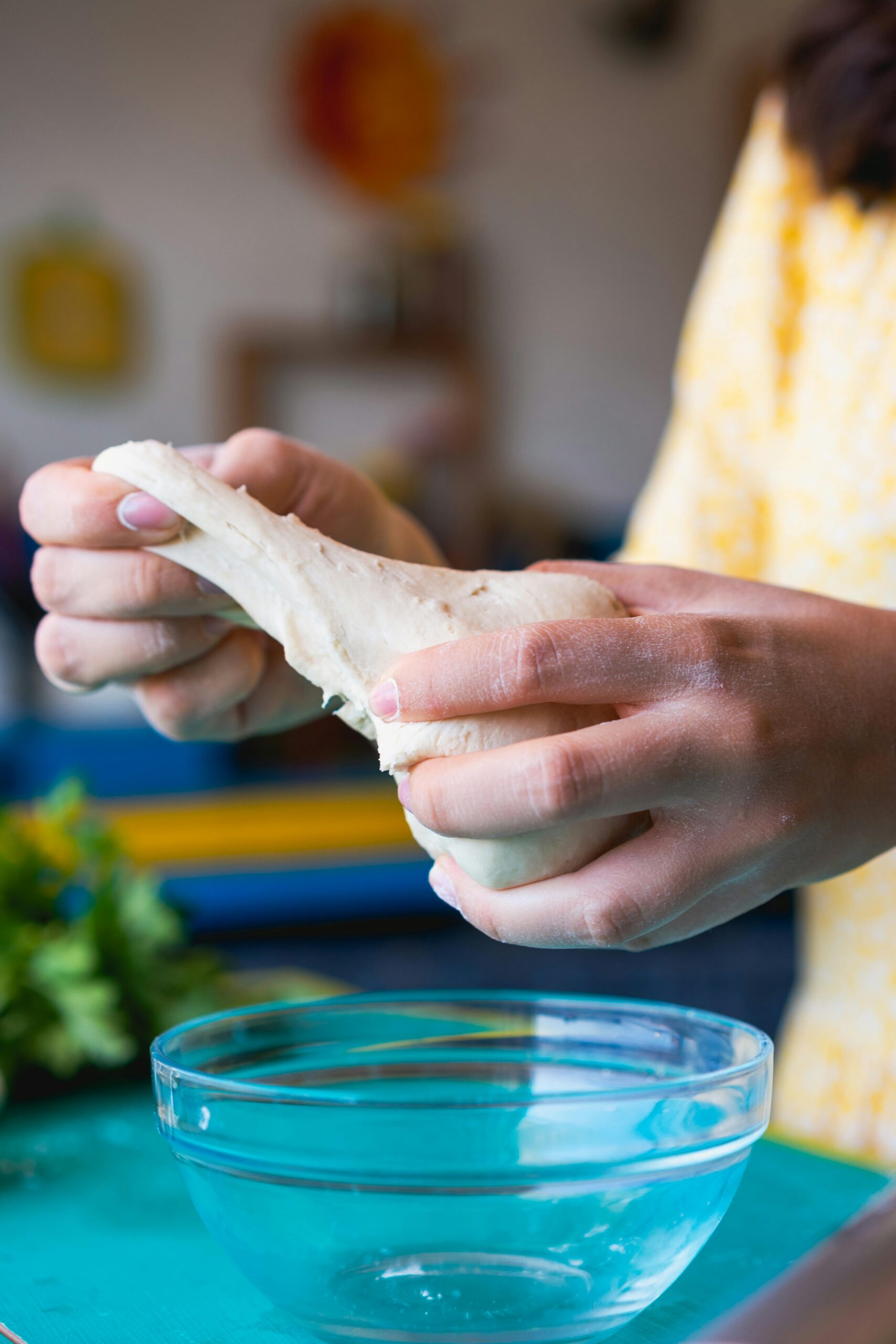 A woman kneads pizza dough in a bowl, preparing to create a delicious homemade pizza.