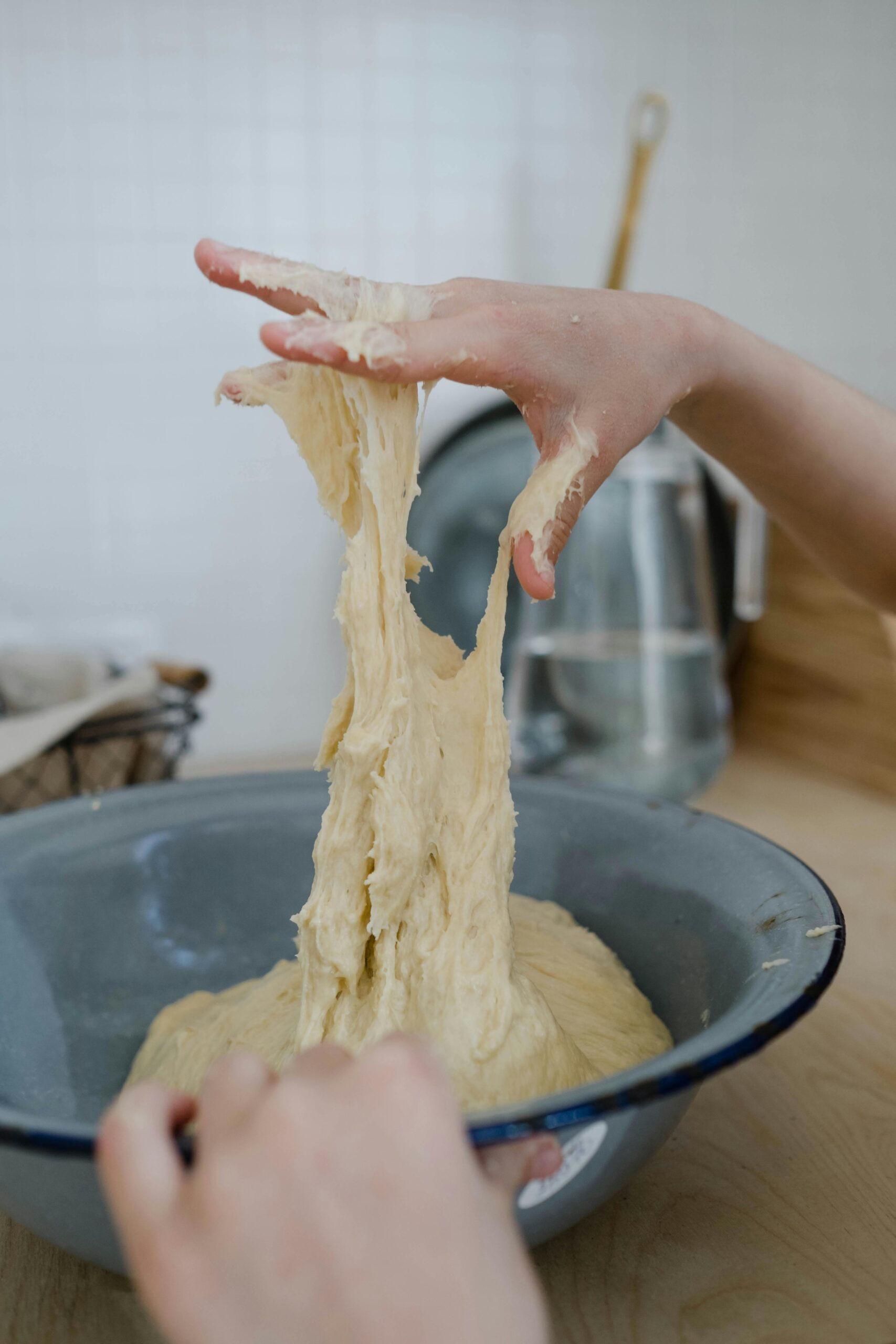 A hand reaching into a bowl of pizza dough, demonstrating the technique of kneading for perfect pizza preparation.