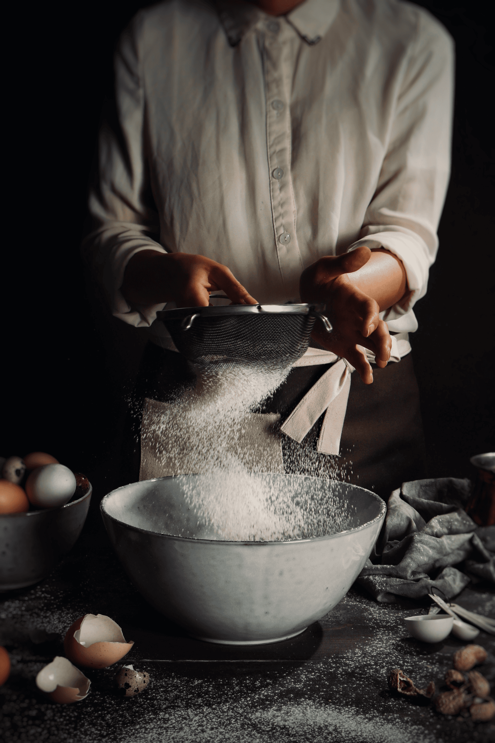 A woman is mixing flour in a bowl, preparing ingredients for baking.