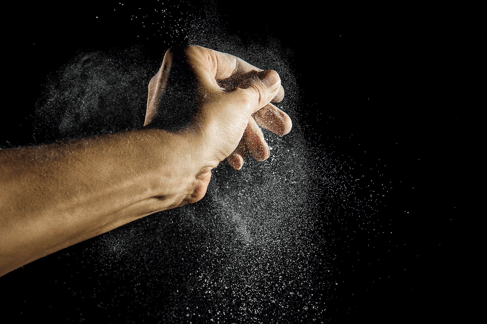 A hand holds a small amount of white powder, representing either bread flour or cake flour for baking purposes.