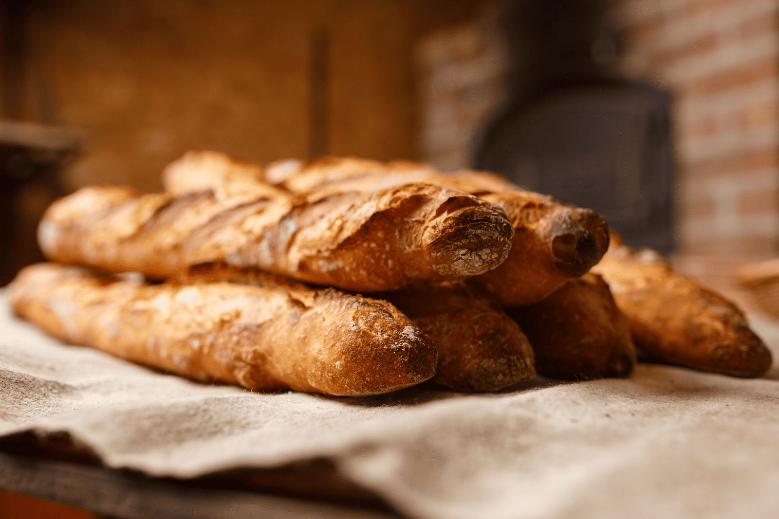 Freshly baked French bread resting on a wooden table in a cozy bakery setting.