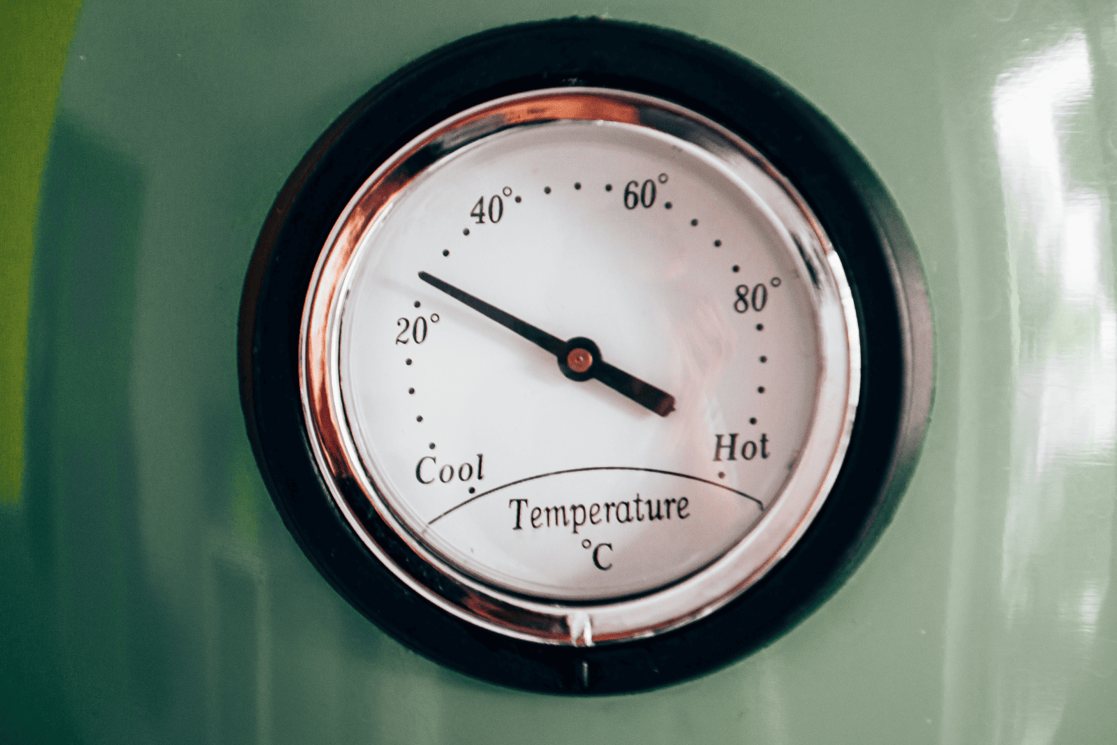 A thermometer mounted on a green wall, possibly indicating temperature for baking bread