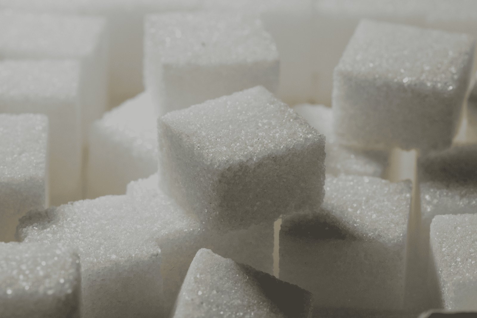 Close-up of white sugar cubes stacked on a surface, highlighting their texture and crystalline structure